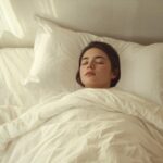 Person sleeping peacefully under white bedding